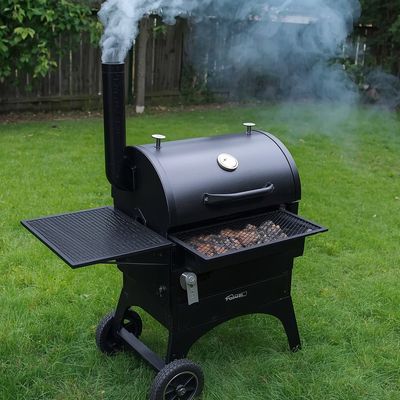 A backyard smoker with smoke rolling out of the stack